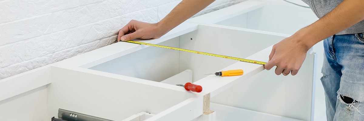 Using a measuring tape to check measurements for cabinets in a commercial kitchen
